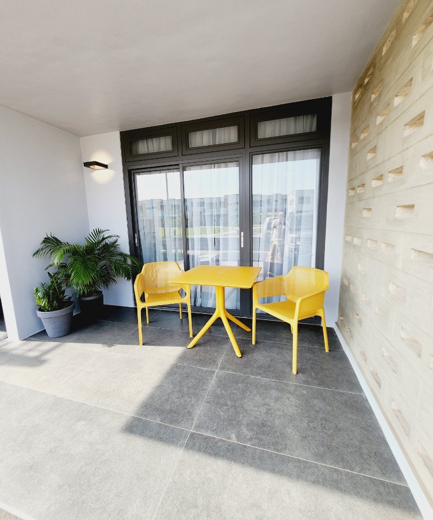 Outdoor patio with yellow bistro set and breeze-block wall